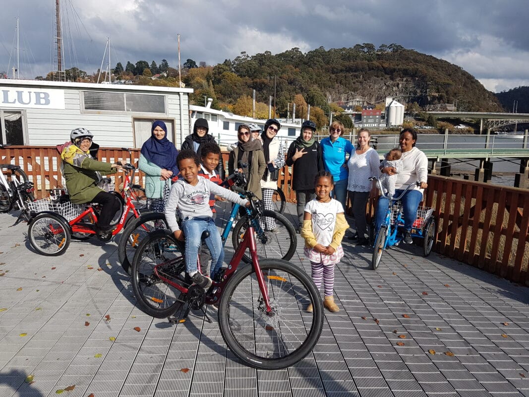A group of women and children with bikes pose as a group on the Seaport Bridge in Launceston witht he gorge in the background.