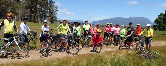 Group of Riders stand in a line in front of Mt Roland.